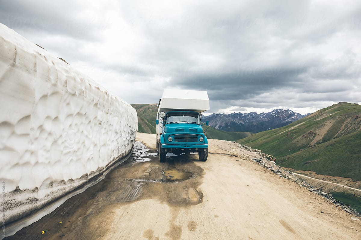 camping truck in high alpine scenery beside huge snow wall, kyrgyzstan