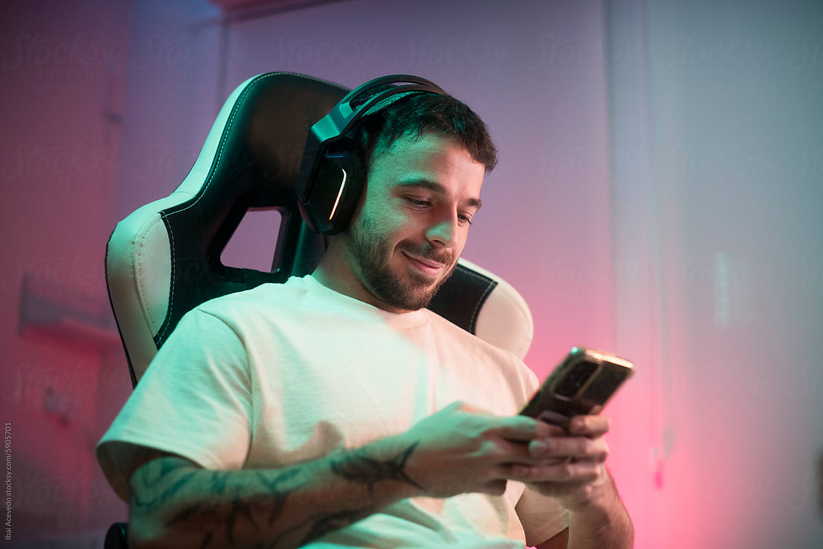 Smiling man using phone on video gaming chair