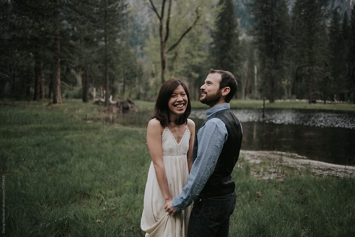 Elopement couple laughing and holding hands in Yosemite valley by river