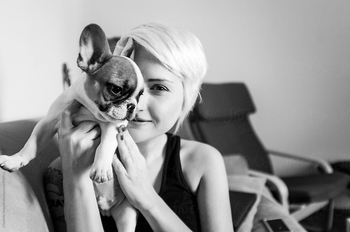 Blonde woman holding a cute french bulldog puppy