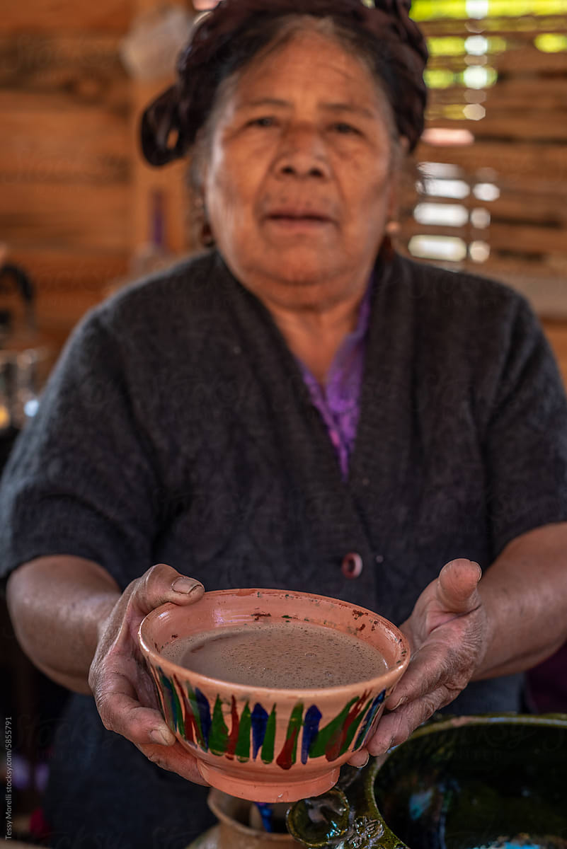 Senior seller offering a cup of Atole