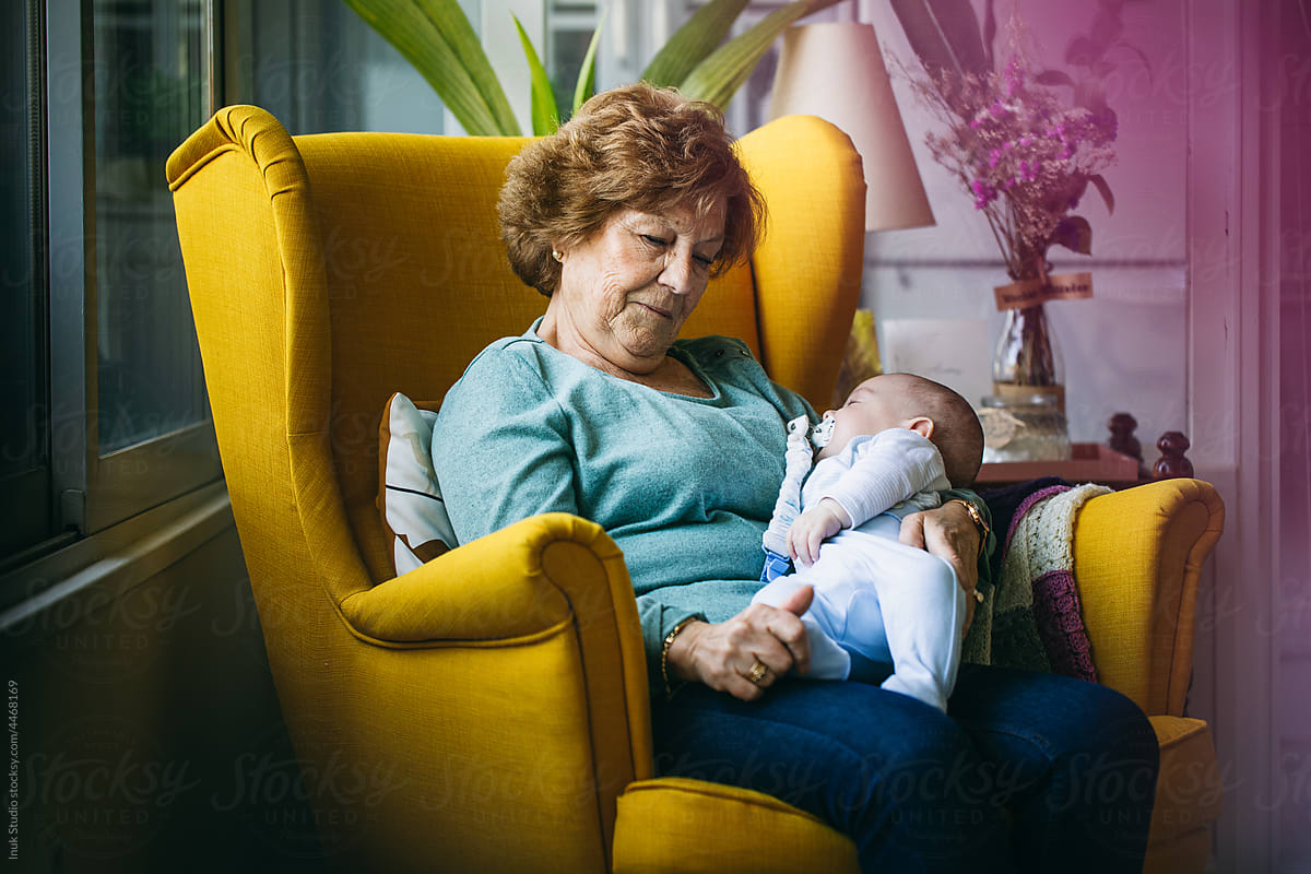 Grandmother hugging sleeping baby in armchair