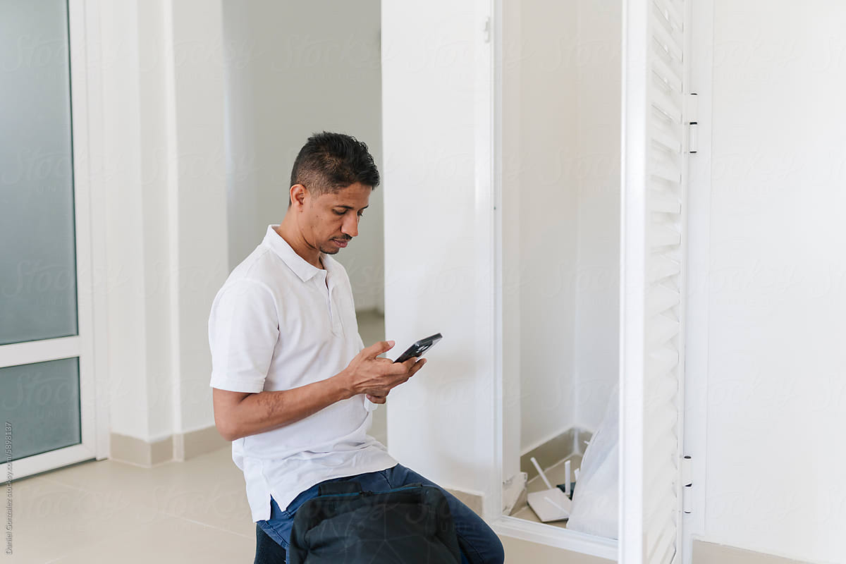 Man kneeling while browsing on smartphone