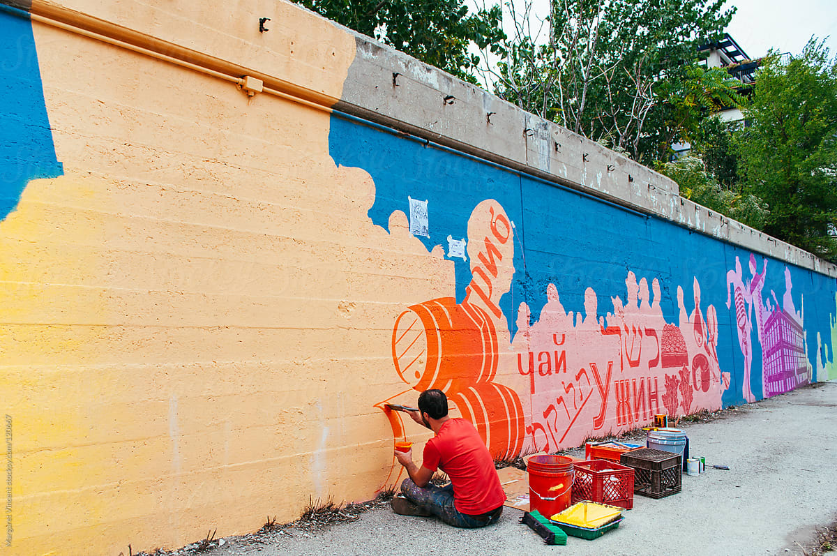 artist paints mural on a city street
