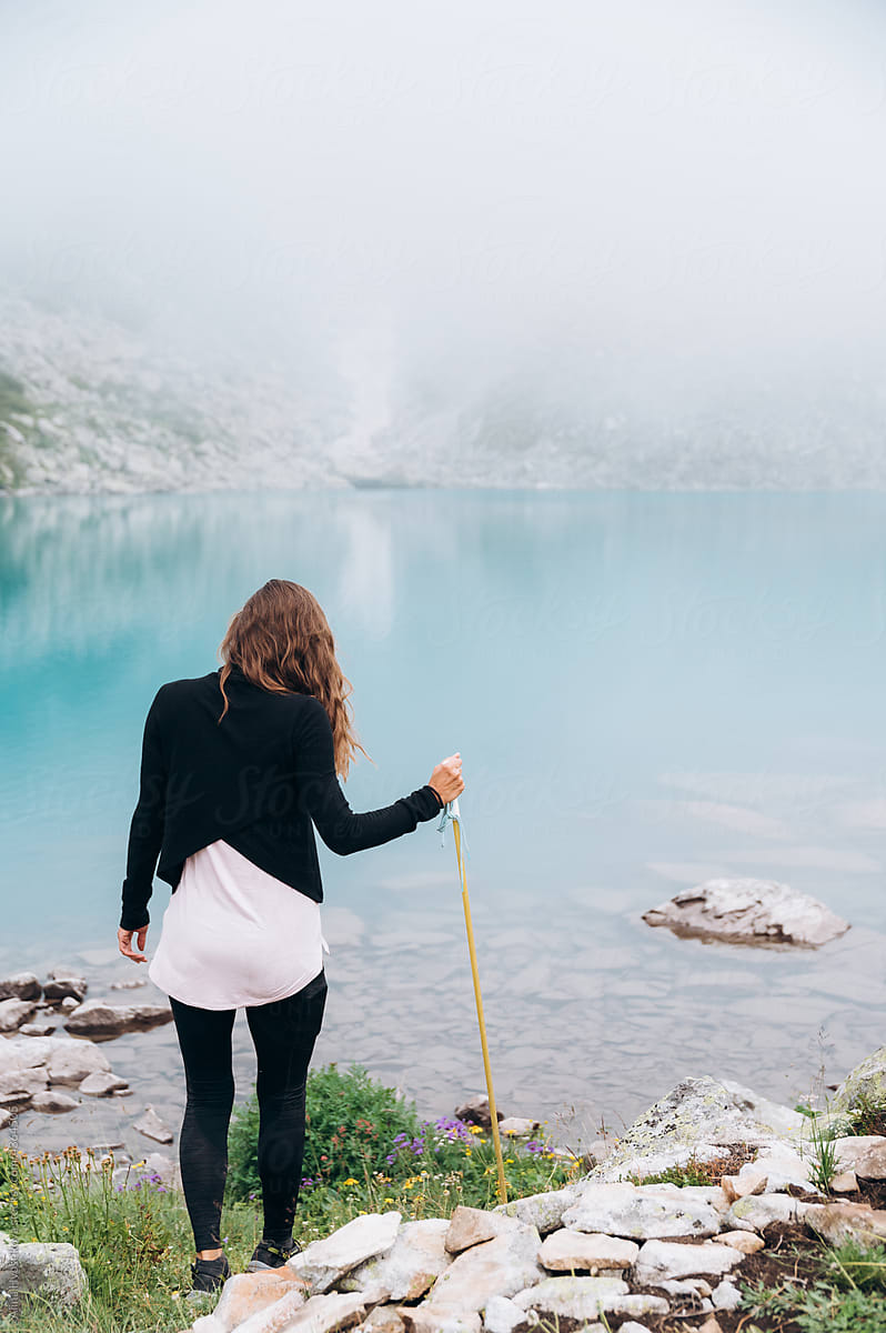 Female hiker standing on lake shore in mountains