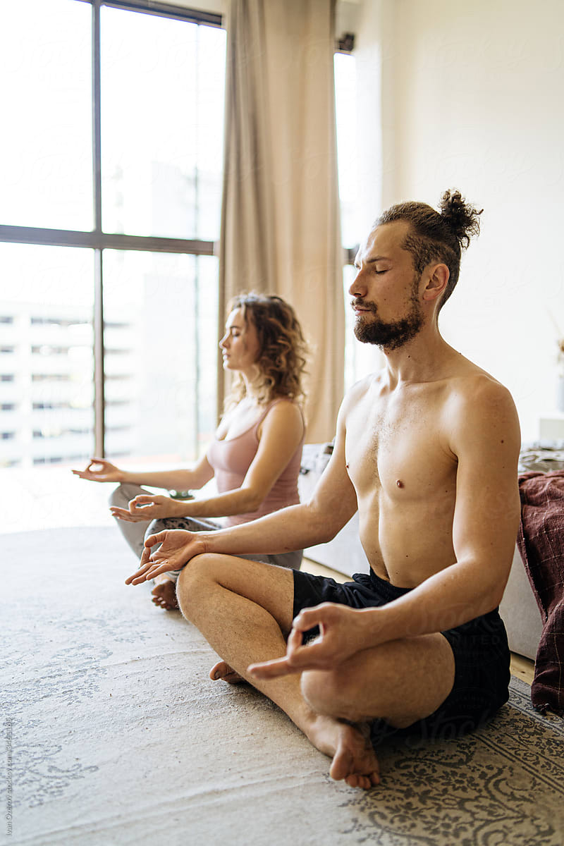 man and woman meditating in their bedroom