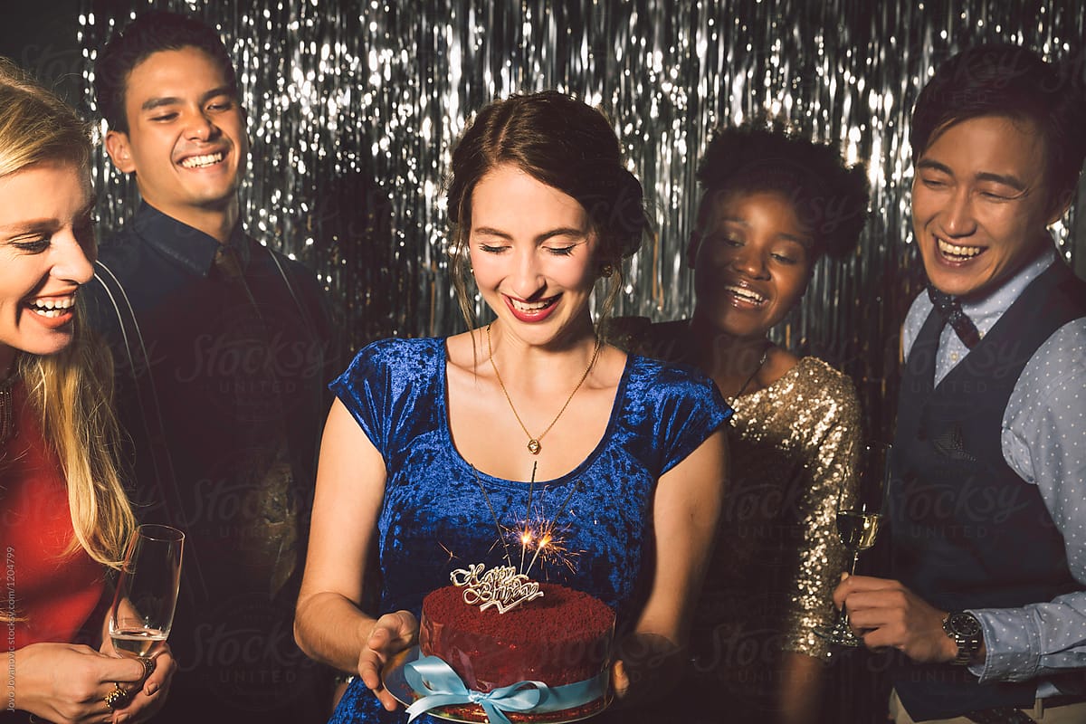 Woman holds a birthday cake at a party