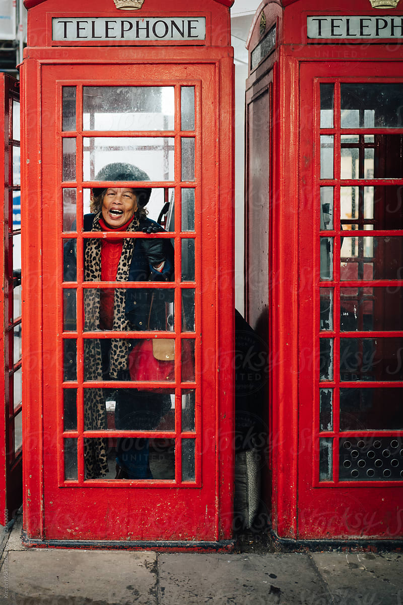 Older woman giggling in phone box