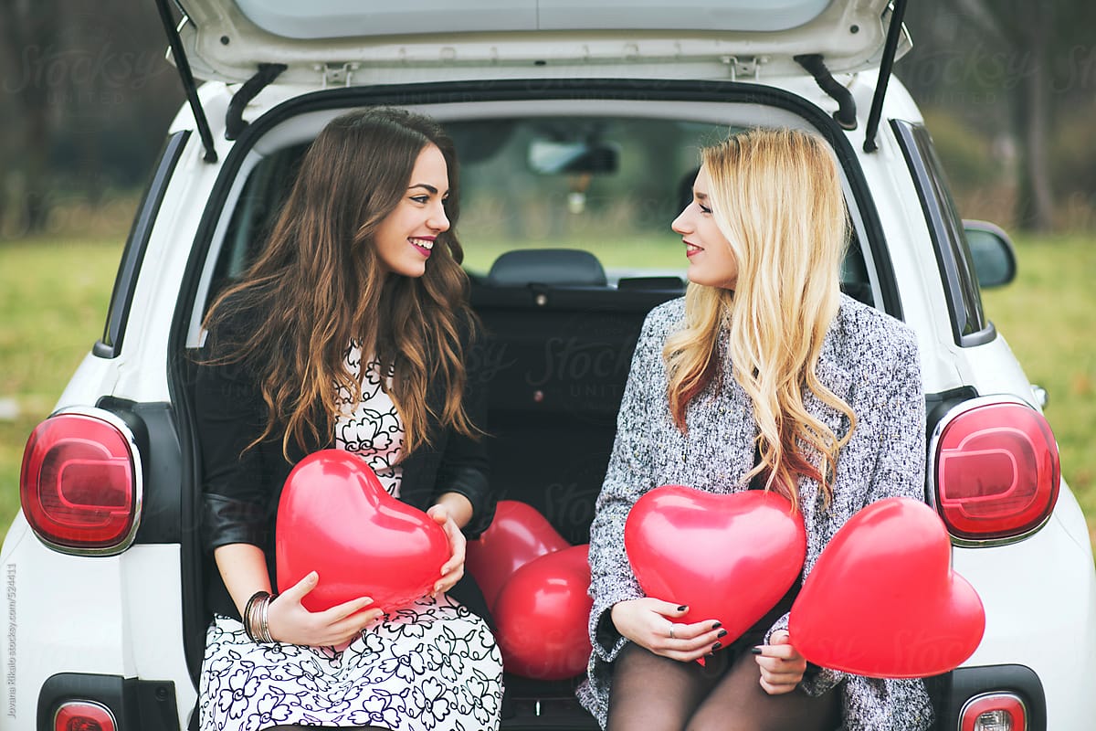 Two female friends holding heart shapped balloons for Valentine's day