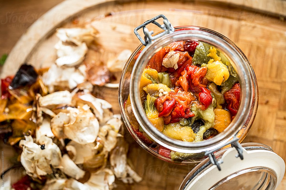 A jar with pickled peppers on wooden surface