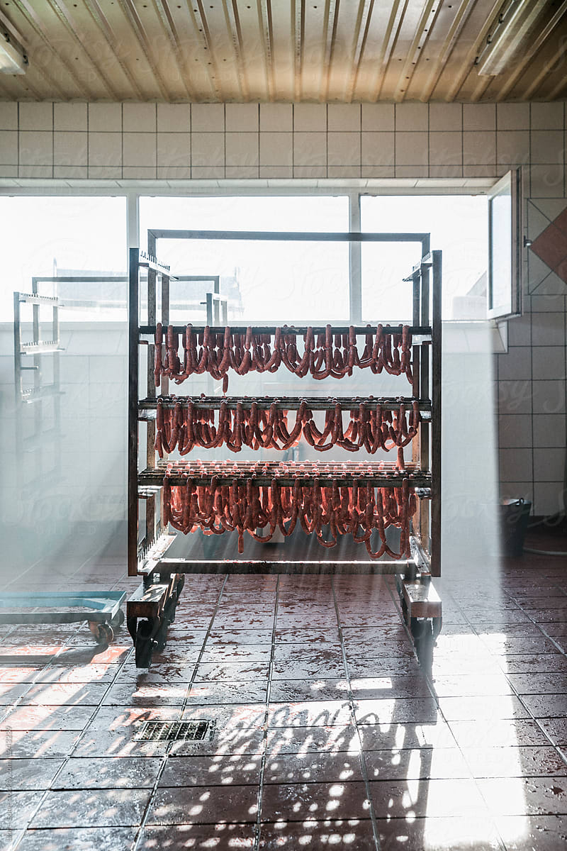 Raw sausages hanging on mobile rack in a butcher shop