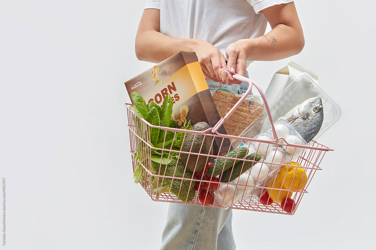 Fresh groceries in wire basket held by girl.
