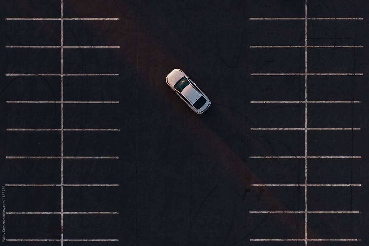 white sedan car in the parking, drone top-down view