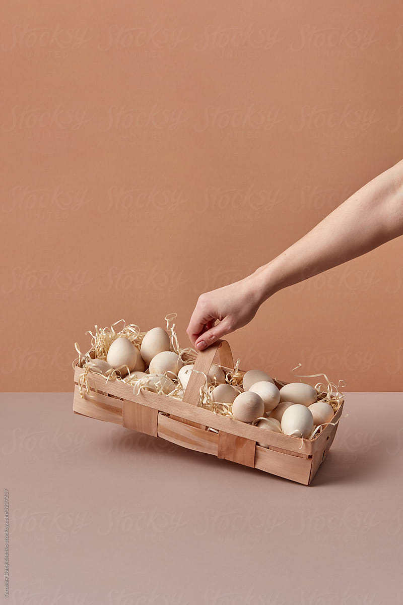 Woman holds basket with wooden Easter eggs.
