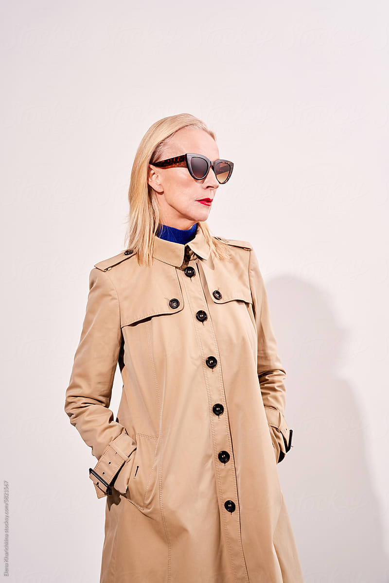 Stylish senior model wearing beige trench coat and vintage glasses