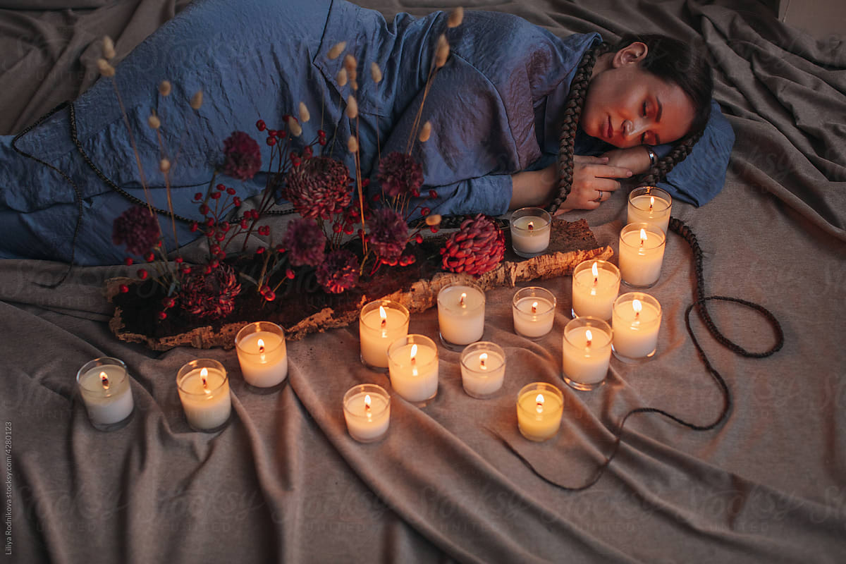Woman sleeping on floor near candles