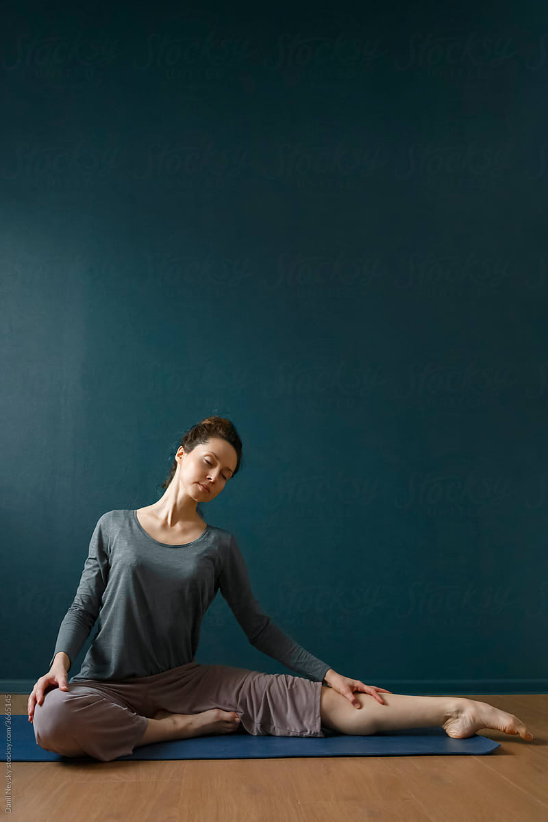 Young female doing yoga on floor in studio