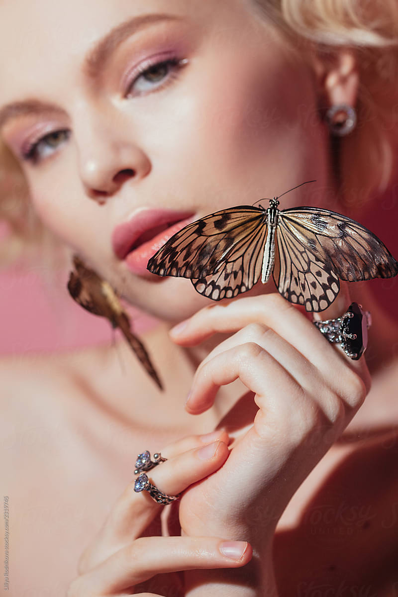 Charming young woman holding butterflies in front of her face