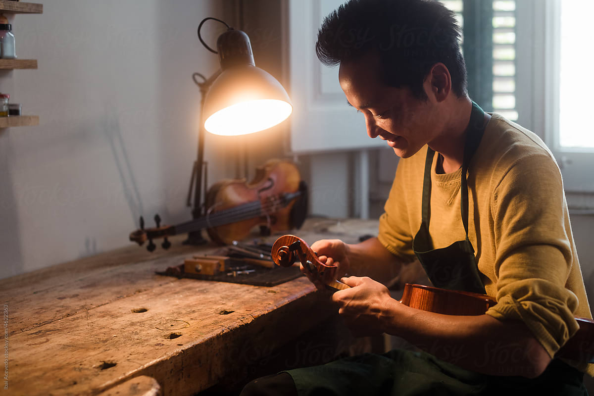 Smiling luthier repairing a violin