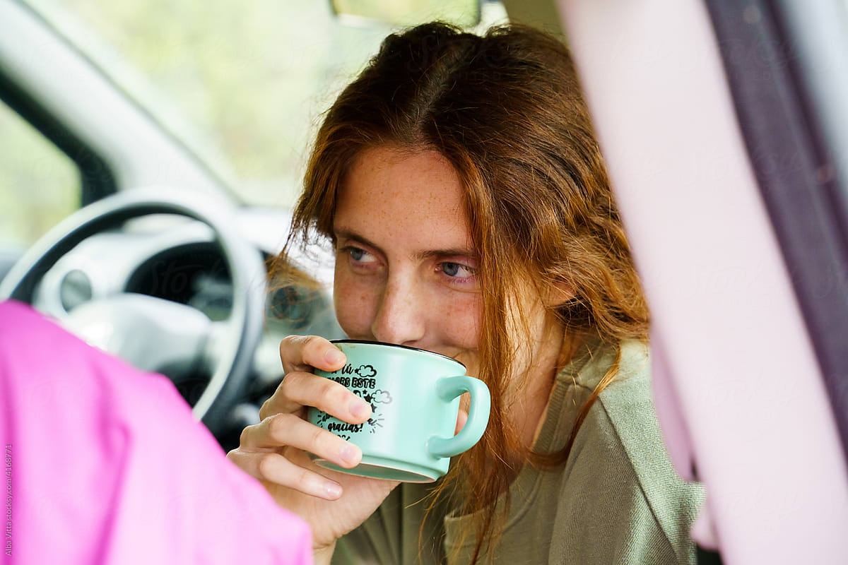Woman drinking coffee inside a car