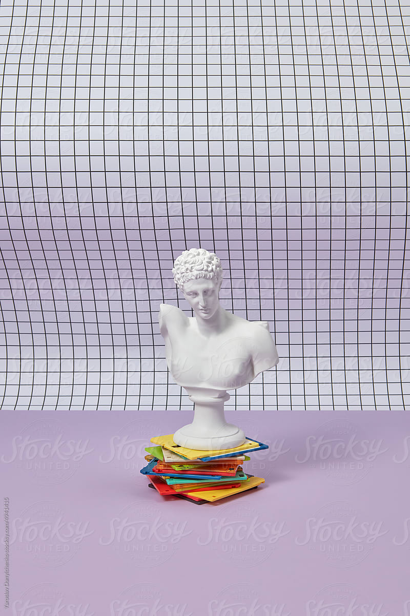 Antique statue on colorful floppy disk stack.
