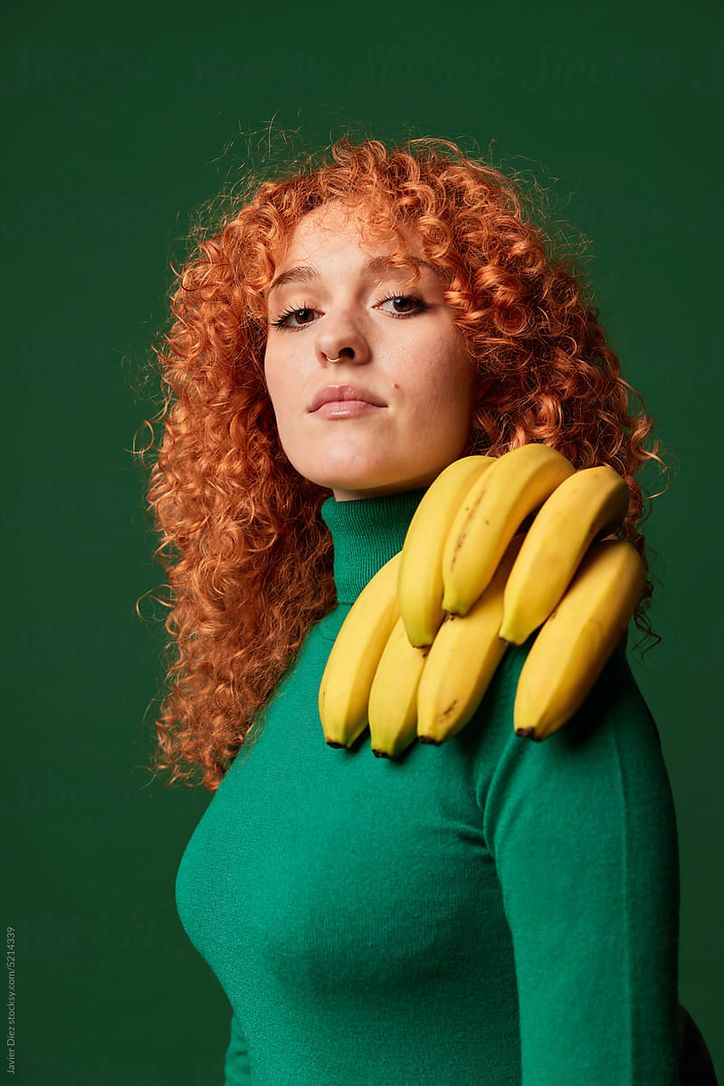 Confident young ginger woman with banana bunch