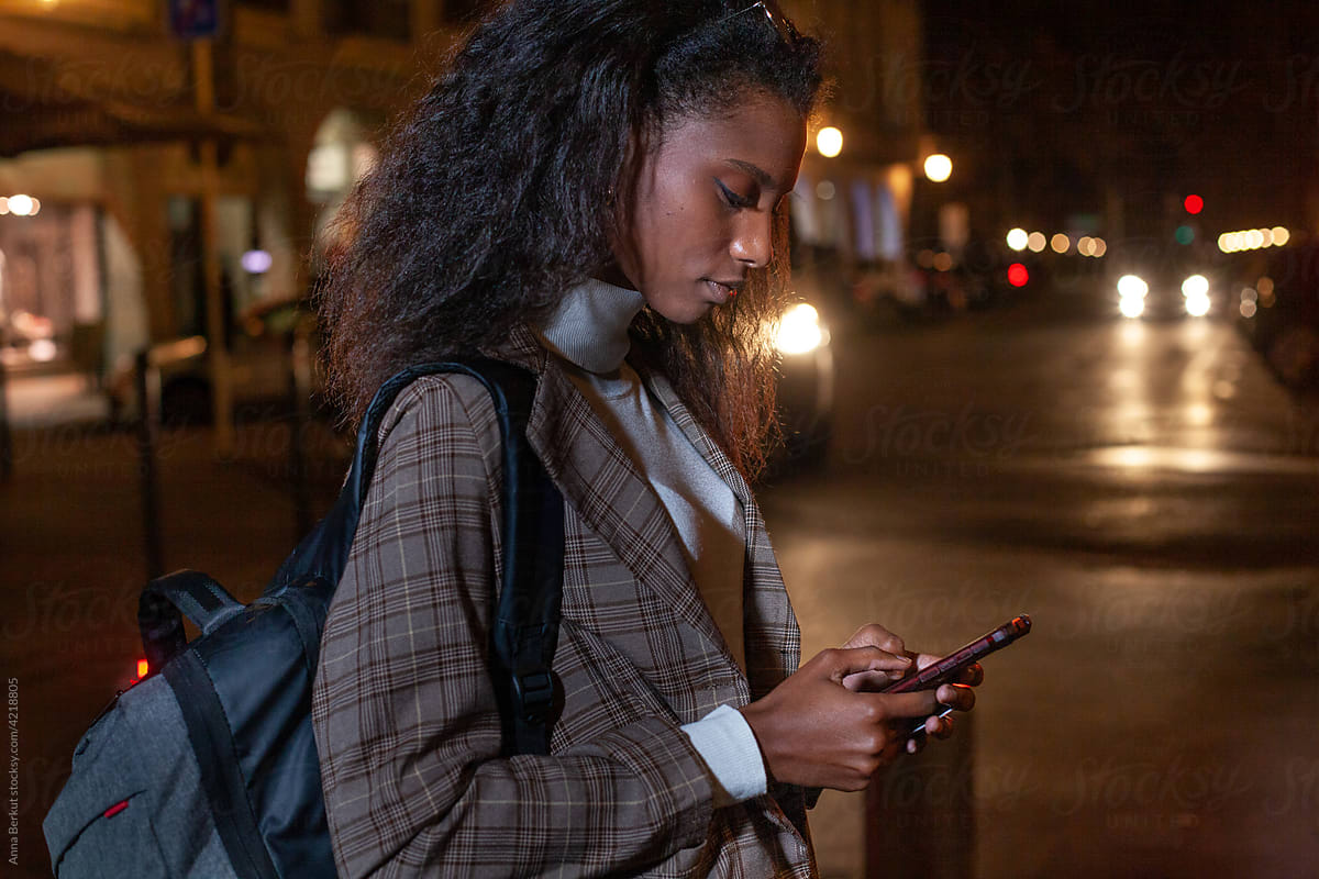 young black woman using smartphone at night outside, mobile phone