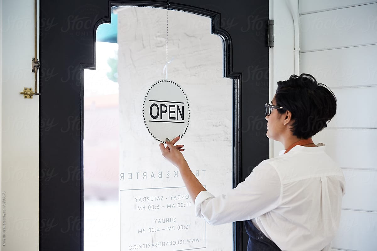 Woman business owner turning open/close sign