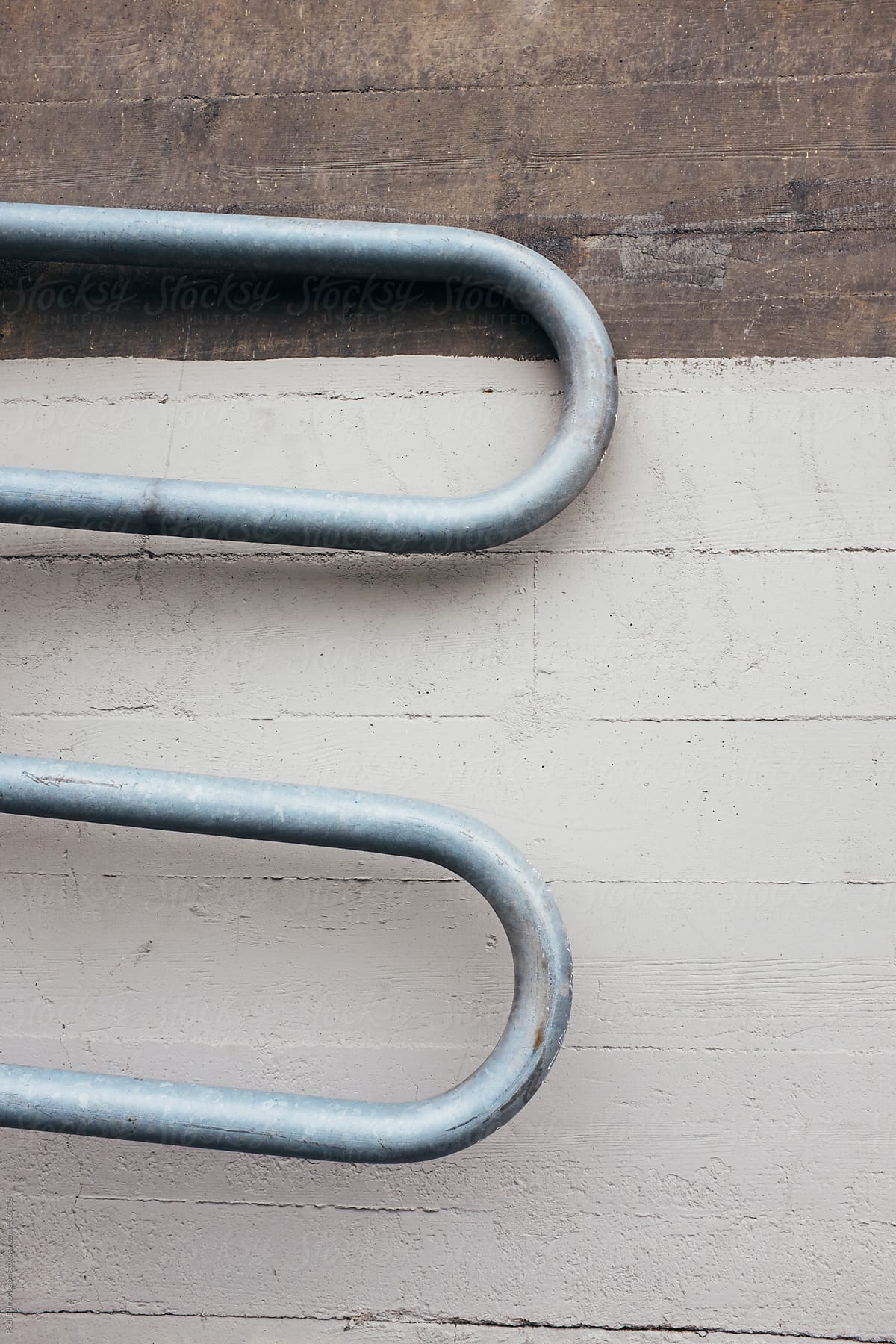 Curved metal bike rack leaning against concrete wall