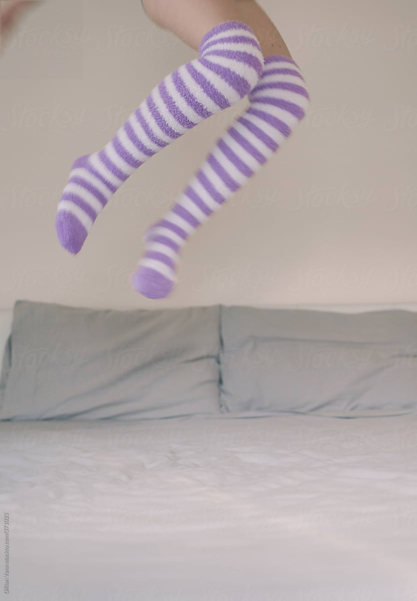 girl jumping on bed in stripy socks