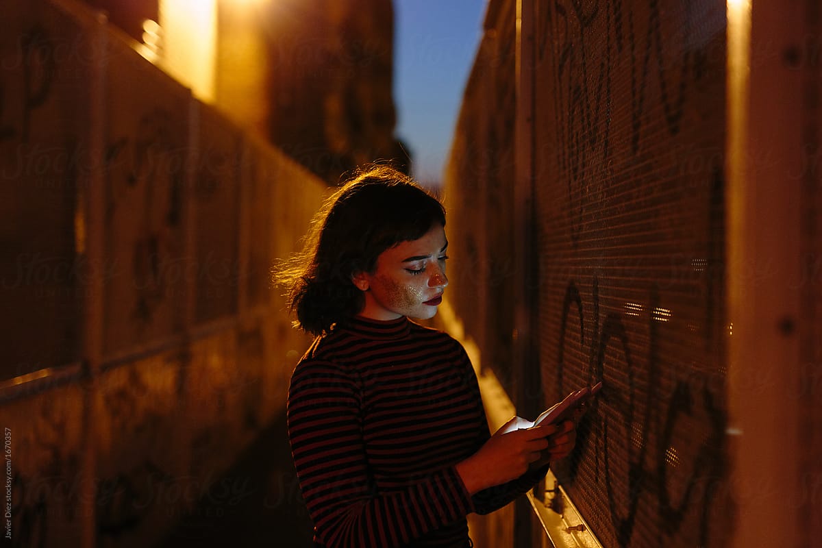 Woman using smartphone near wall in evening