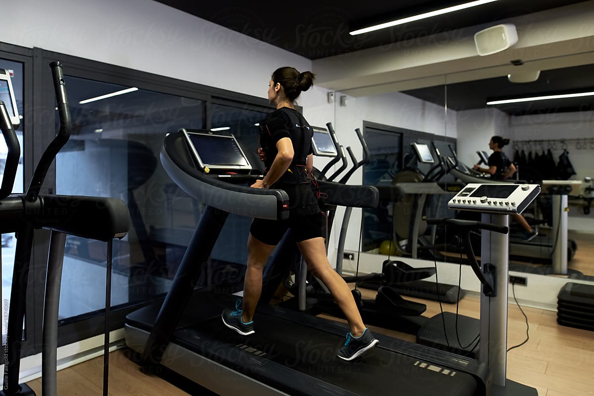 Sportswoman in EMS running on a treadmill in the gym.