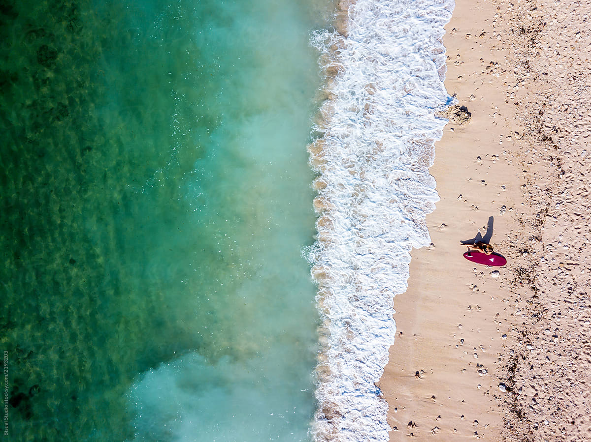 Woman Sunbathing Alone On An Empty Beach With Her Surfboard In Bali By Stocksy Contributor