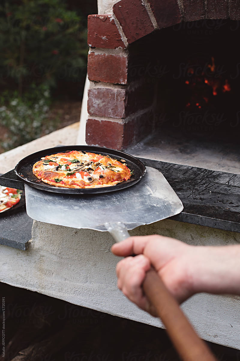 outdoors cooking pizza in wood fire oven