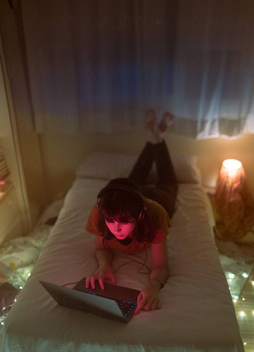 Woman lying on bed using laptop