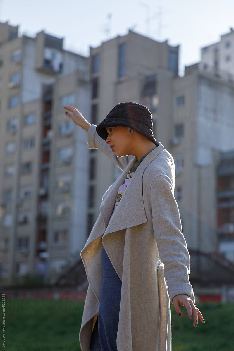 Young woman with hat dancing outside in city