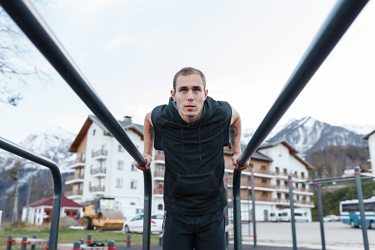 Determined athlete exercising on bars in town - Stock Image - Everypixel