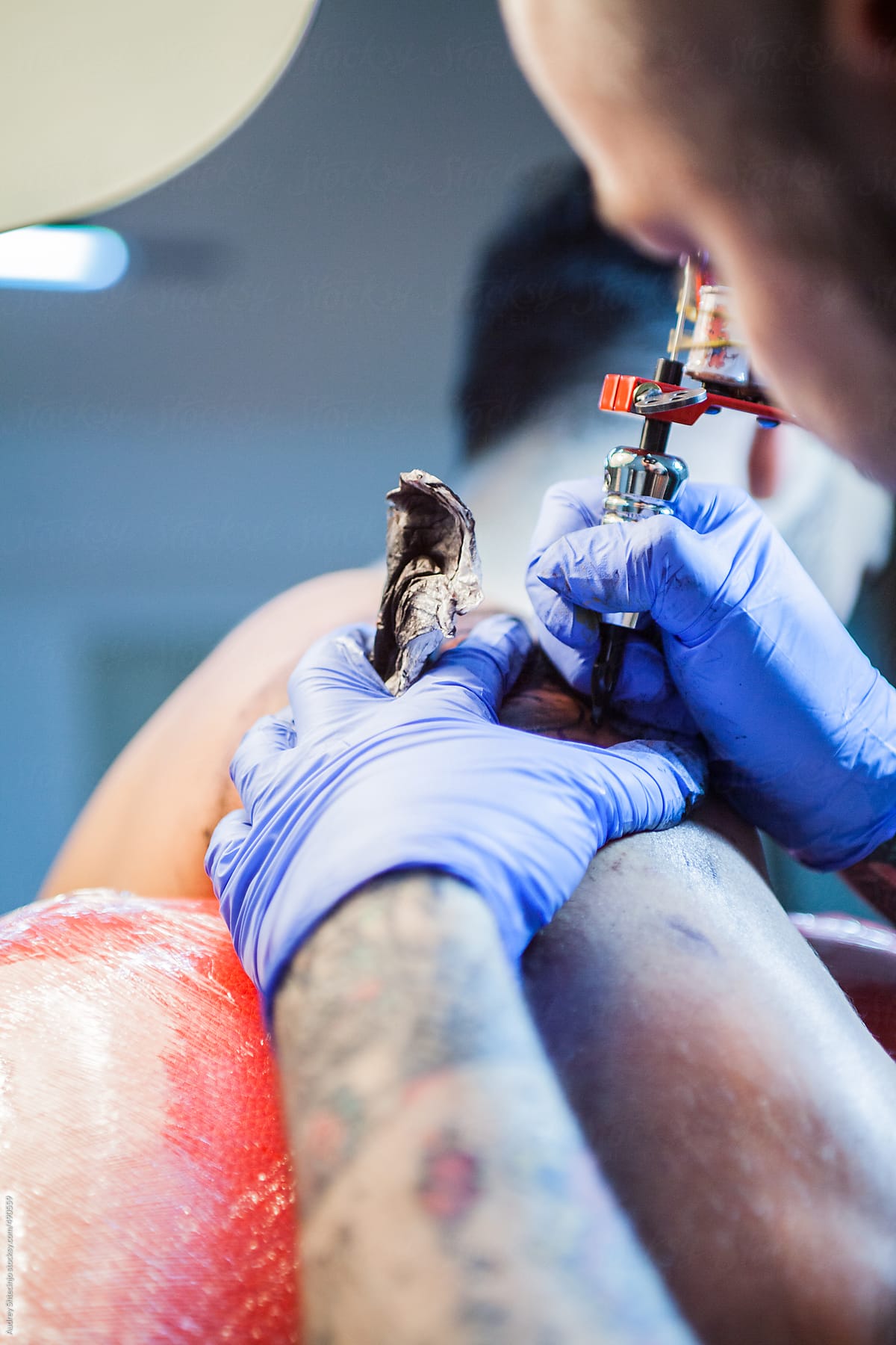 Tattoo artist inking on man\'s skin.