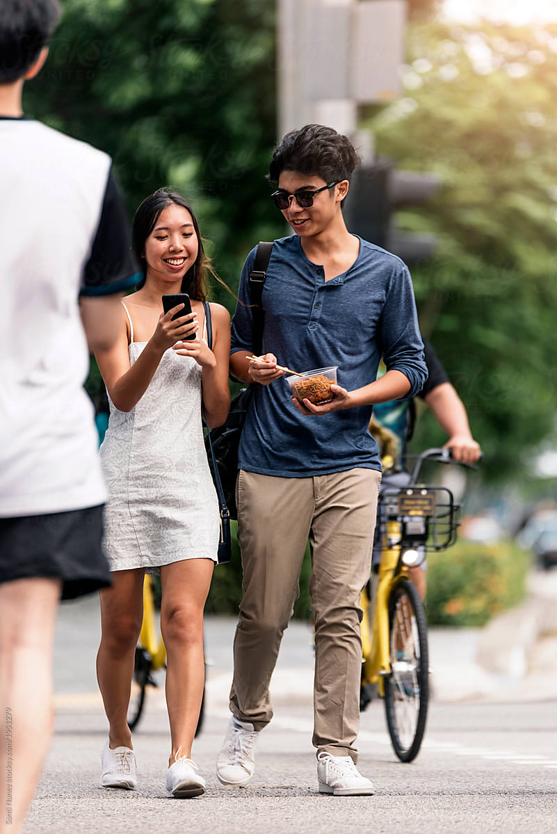 Young asian couple using mobile in the street.