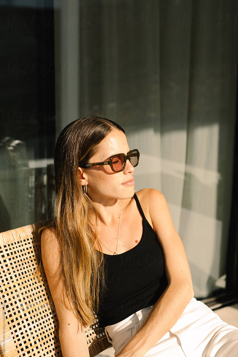 Medium shot portrait of a woman wearing sunglasses lounging in a chair