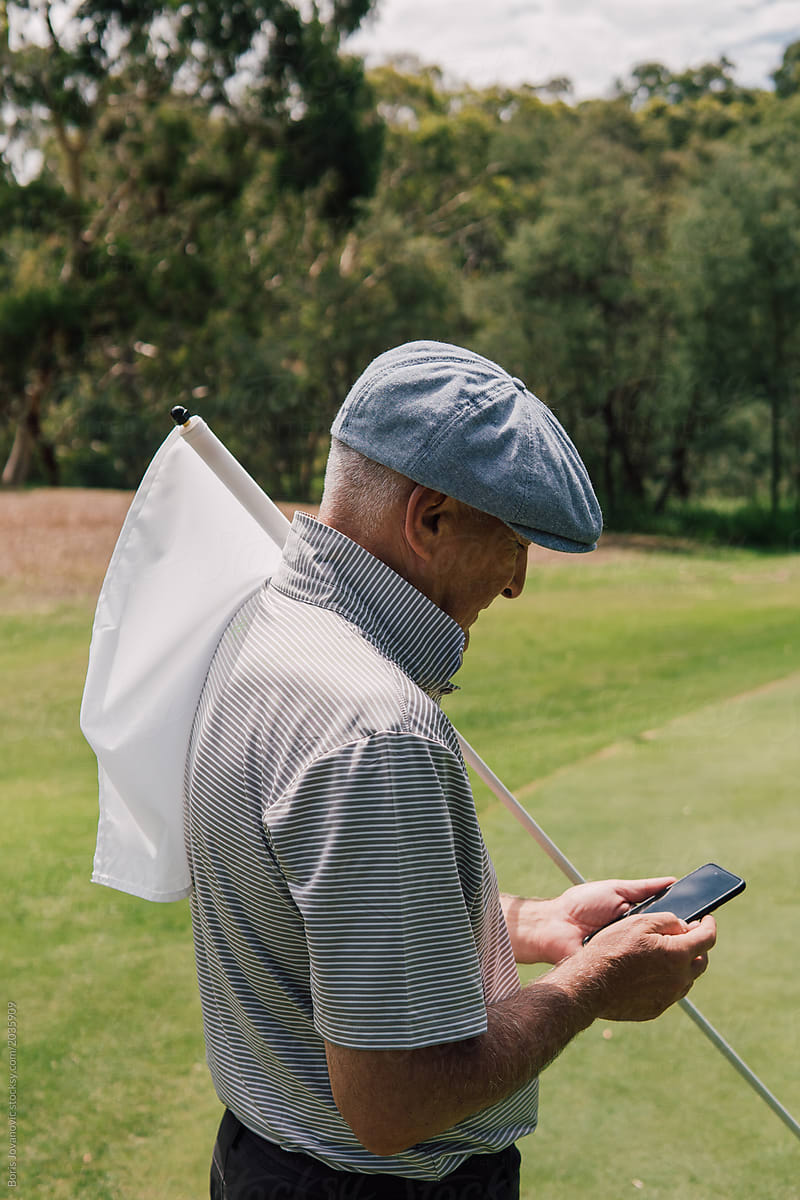 Senior Man Using A Mobile Phone On The Golf Course