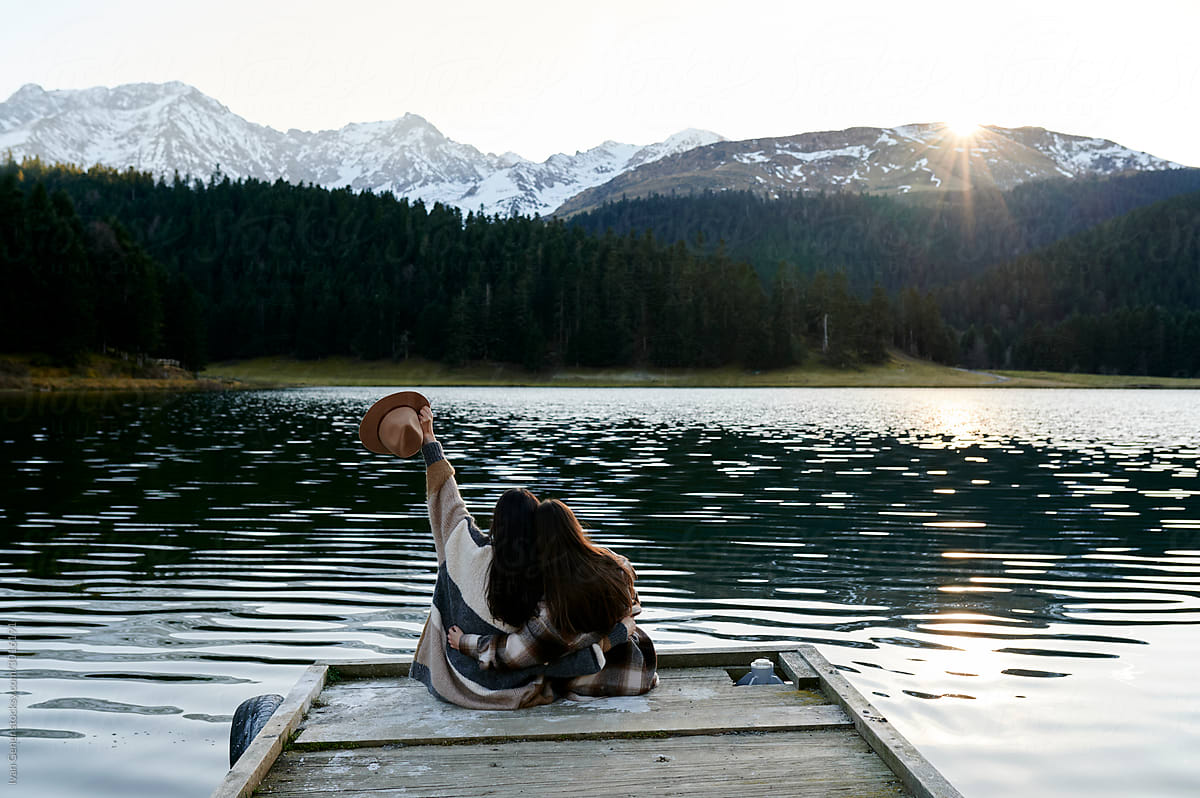 Carefree lesbian couple sitting by an alpine lake