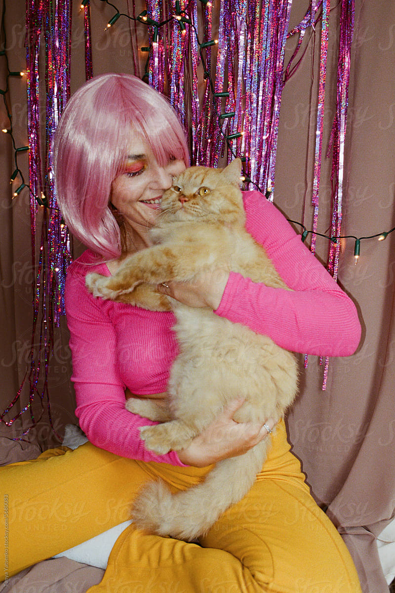 A  woman over a pink tinsel background with a cat