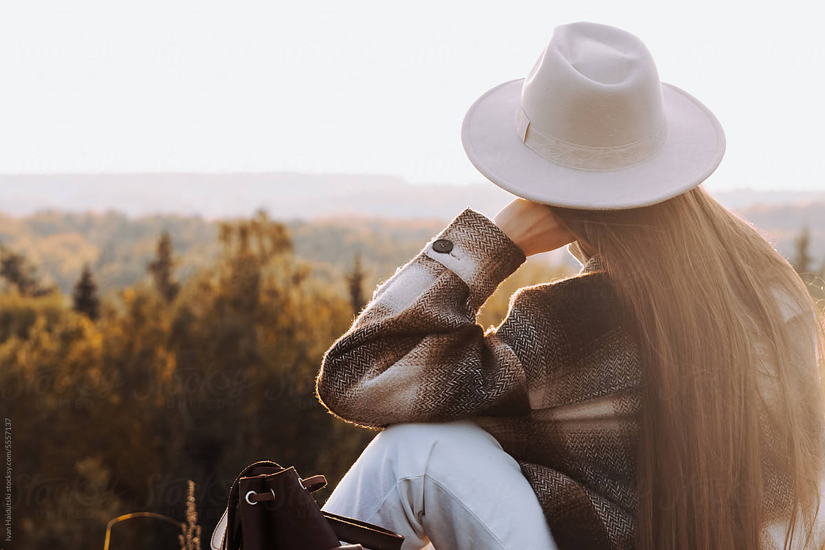 Trendy woman, hat, warm coat, deep in thought, enjoys peaceful autumn