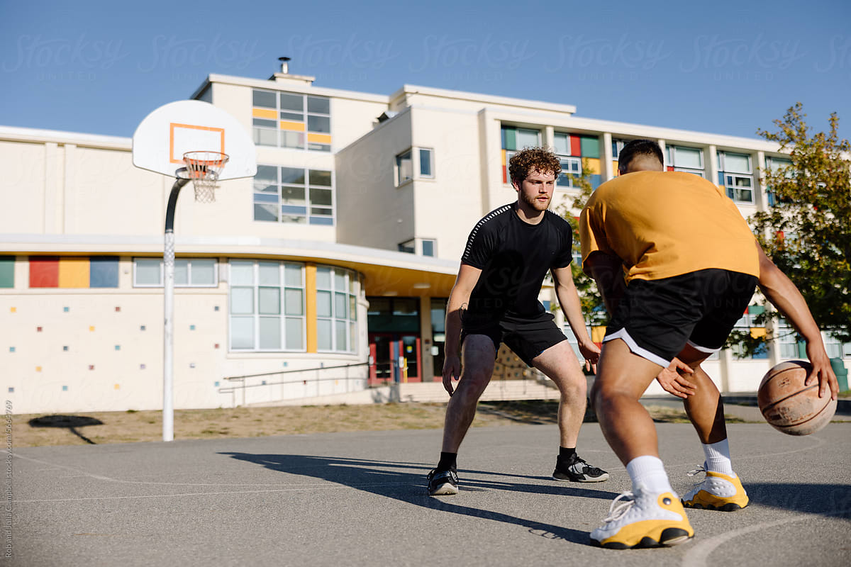 Two men playing one-on-one basketball together outside.