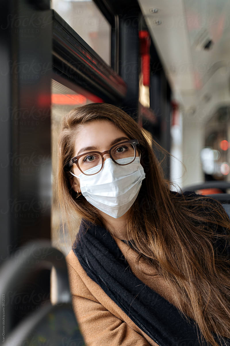 a woman in a medical mask rides a tram