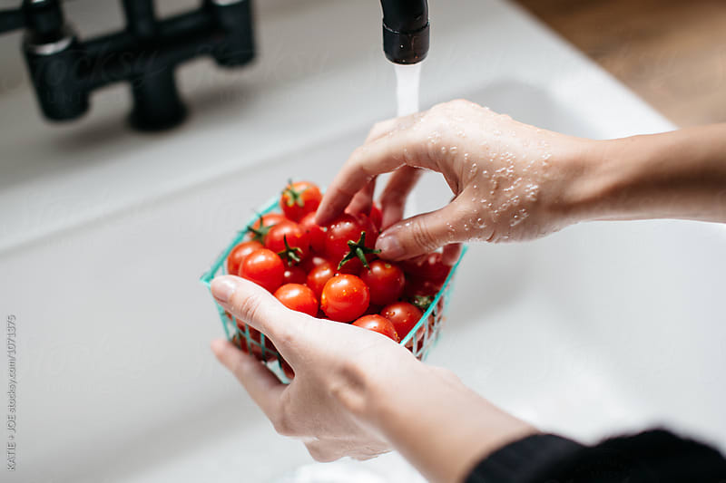 tomatoes being washed in a white sink