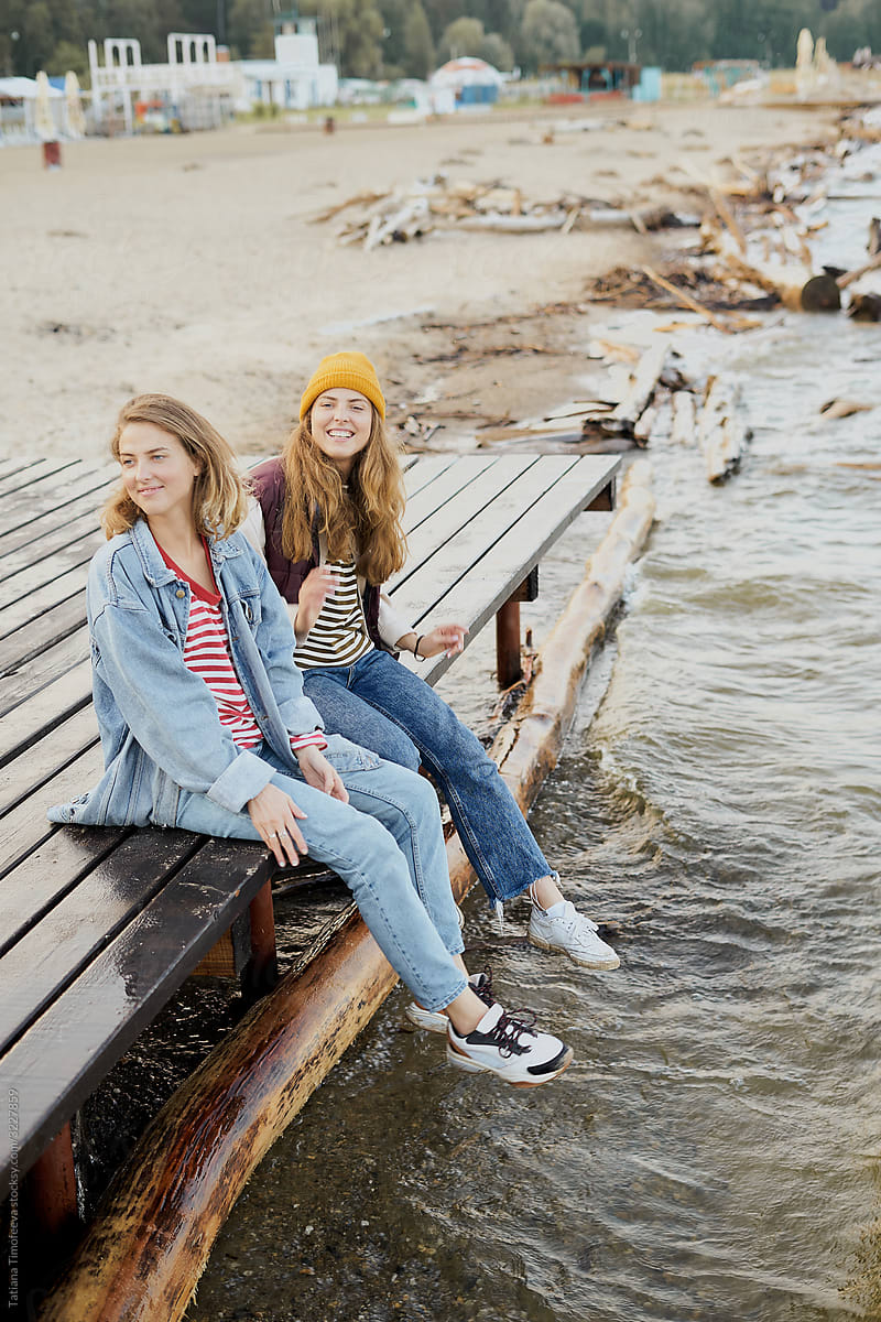 female twins. sisters sit on the beach on a wooden pier