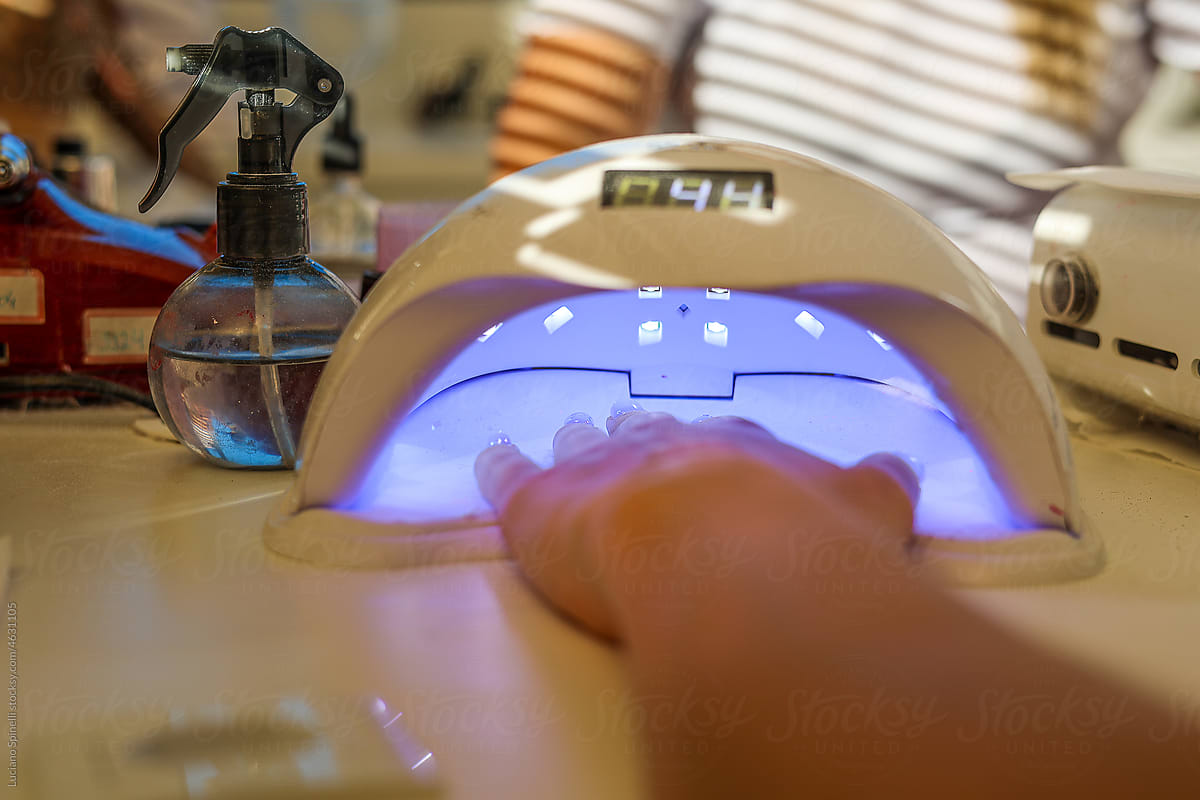 A woman dries her gel-coated nails in a special ultraviolet lamp