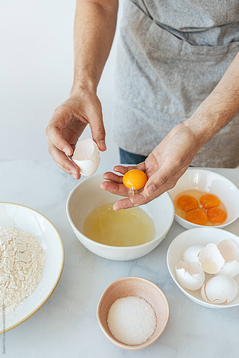 Hand separating egg yolk into bowl